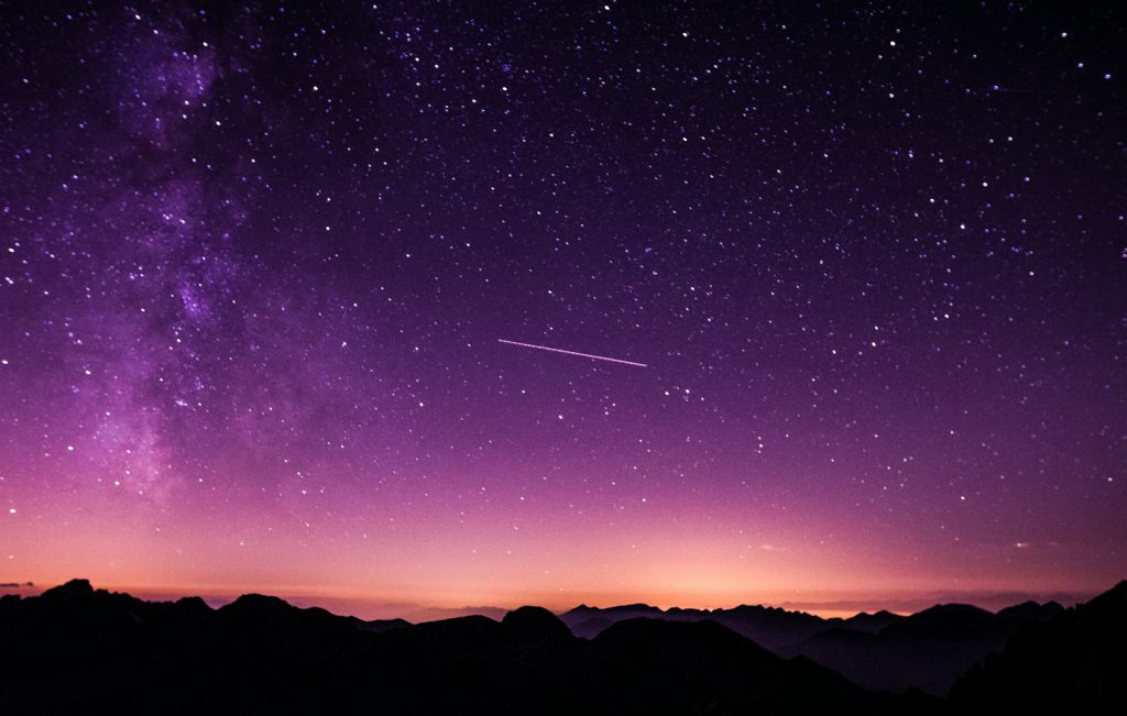 Starry night sky over a dark horizon